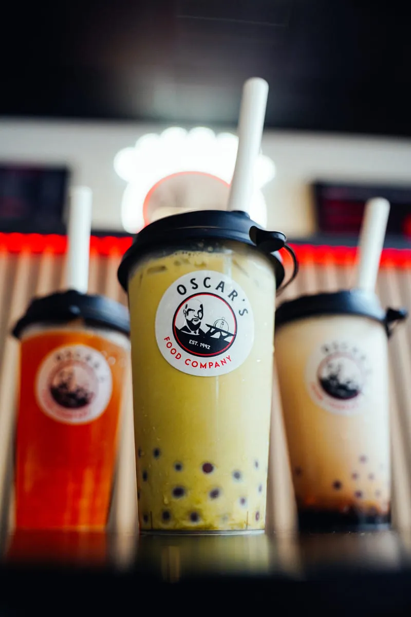 Bekers verse bubbeltea met het logo van Oscar's, voor een warme achtergrond.